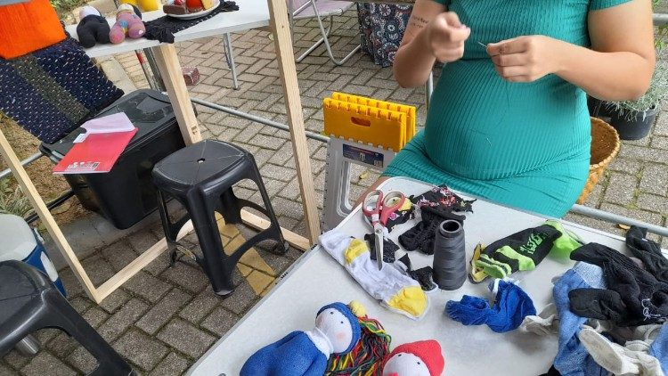 Una donna ospitata nella Casa mentre prepara pupazzi da vendere