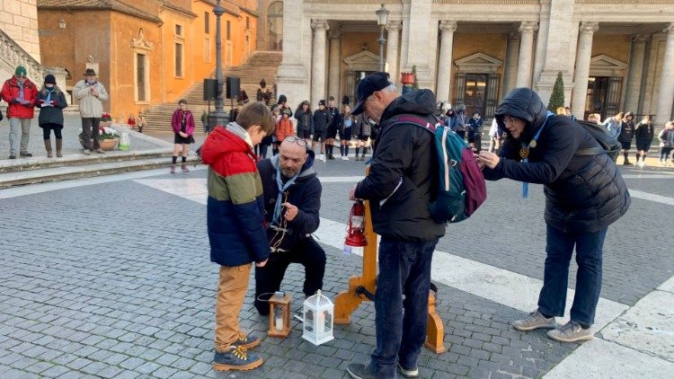 Un piccolo scout ucraino attinge la fiammella dal tripode per consegnarla a tutti i gruppi scout presenti